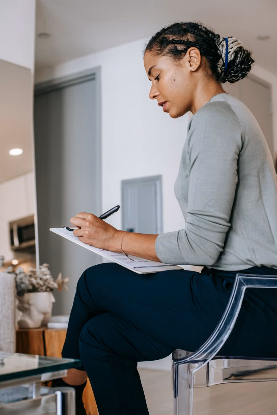 Woman writing in a notebook in a living room — illustrative stock photograph